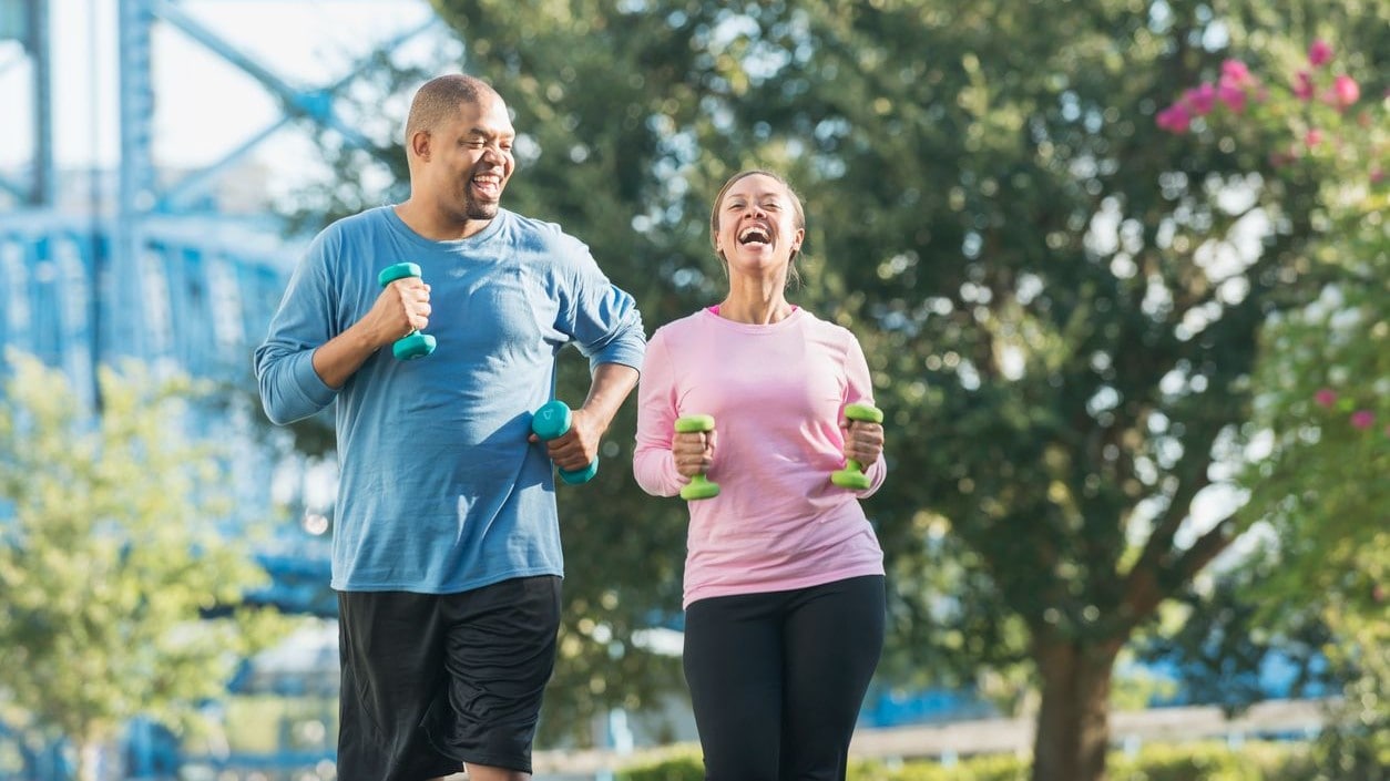 Two people walking with hand weights in an outdoor setting