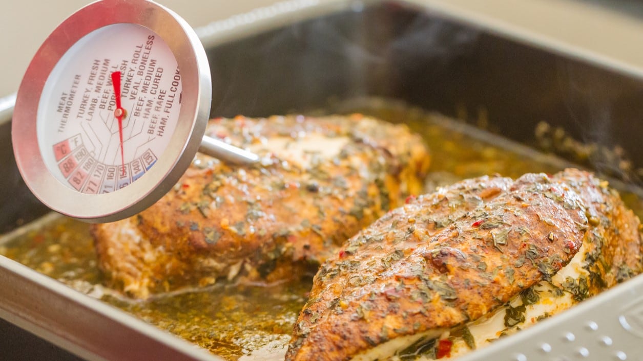 cooked chicken in a pan with a thermometer stuck inside it