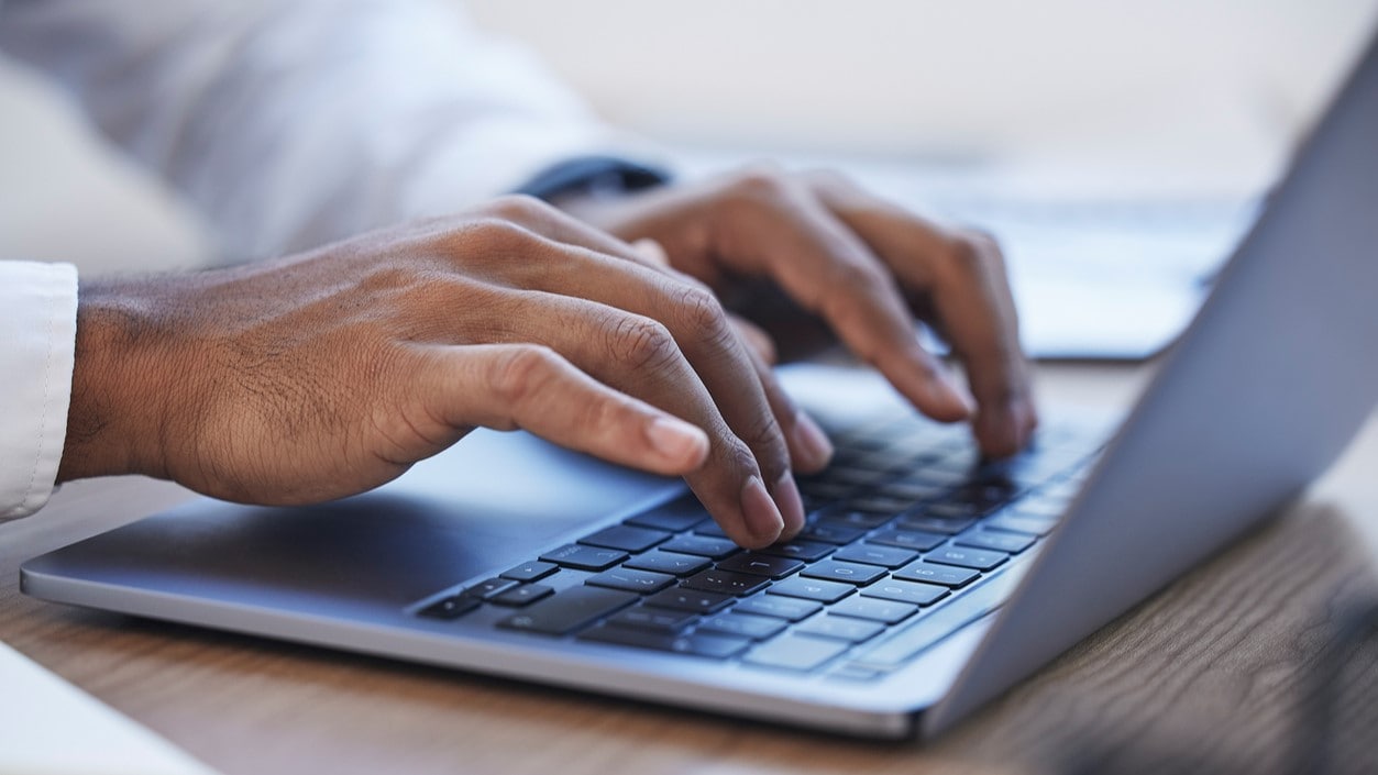 Photograph of laptop and hand typing.