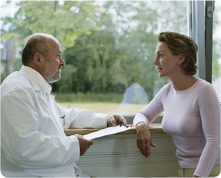 Male doctor holding clipboard and talking to female patient