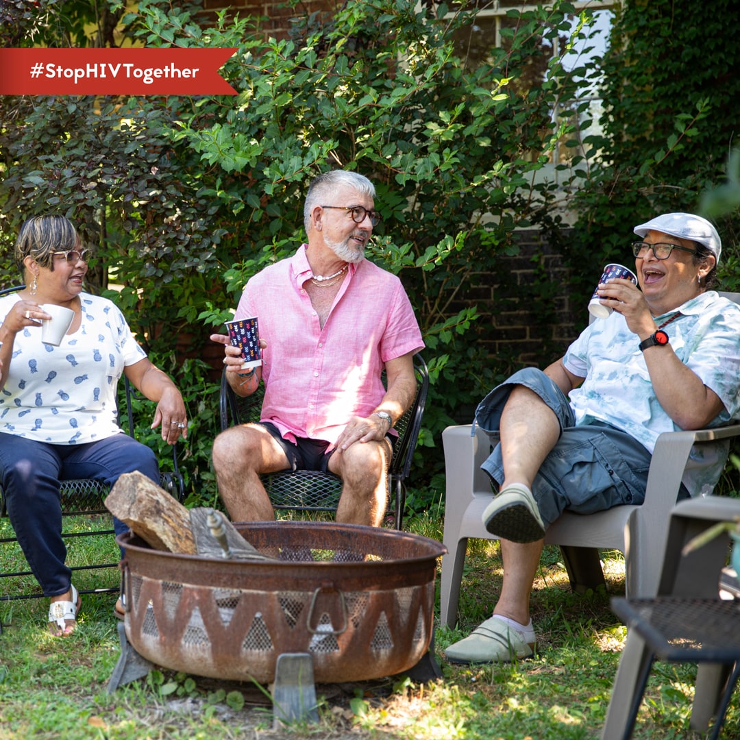 An image of three older adults laughing together while sitting outside.