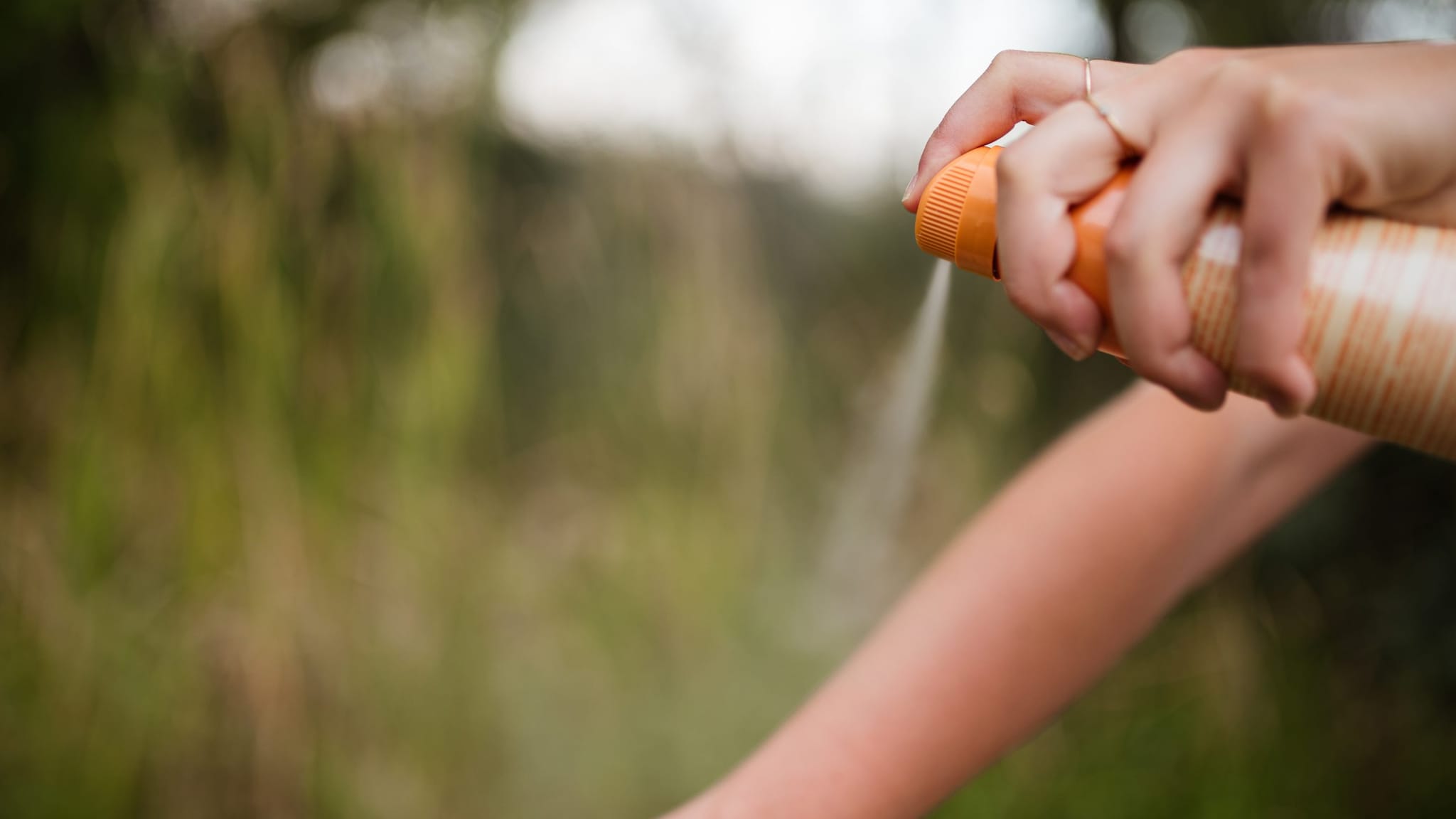 Person spraying insect repellent onto their arm.