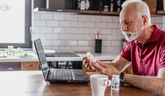 man reading prescription label in his kitchen