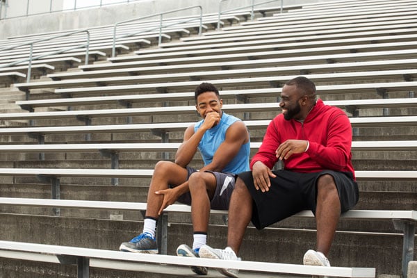 Father and son sitting on the stadium bleachers talking