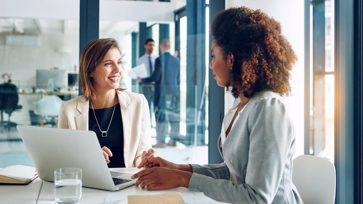 2 women talking while using a laptop computer