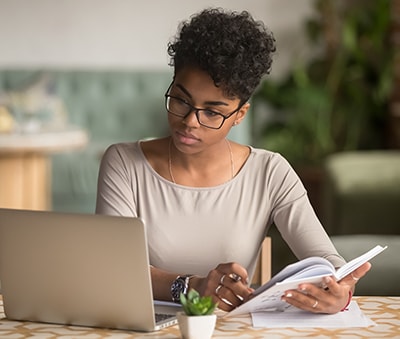 Woman looking at a laptop and taking notes.