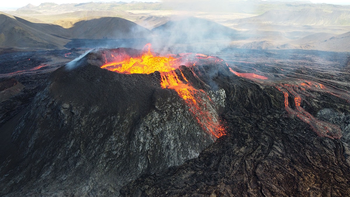 Volcano with lava, ash, and gases spewing out.