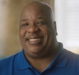 Black male wearing a blue shirt and smiling